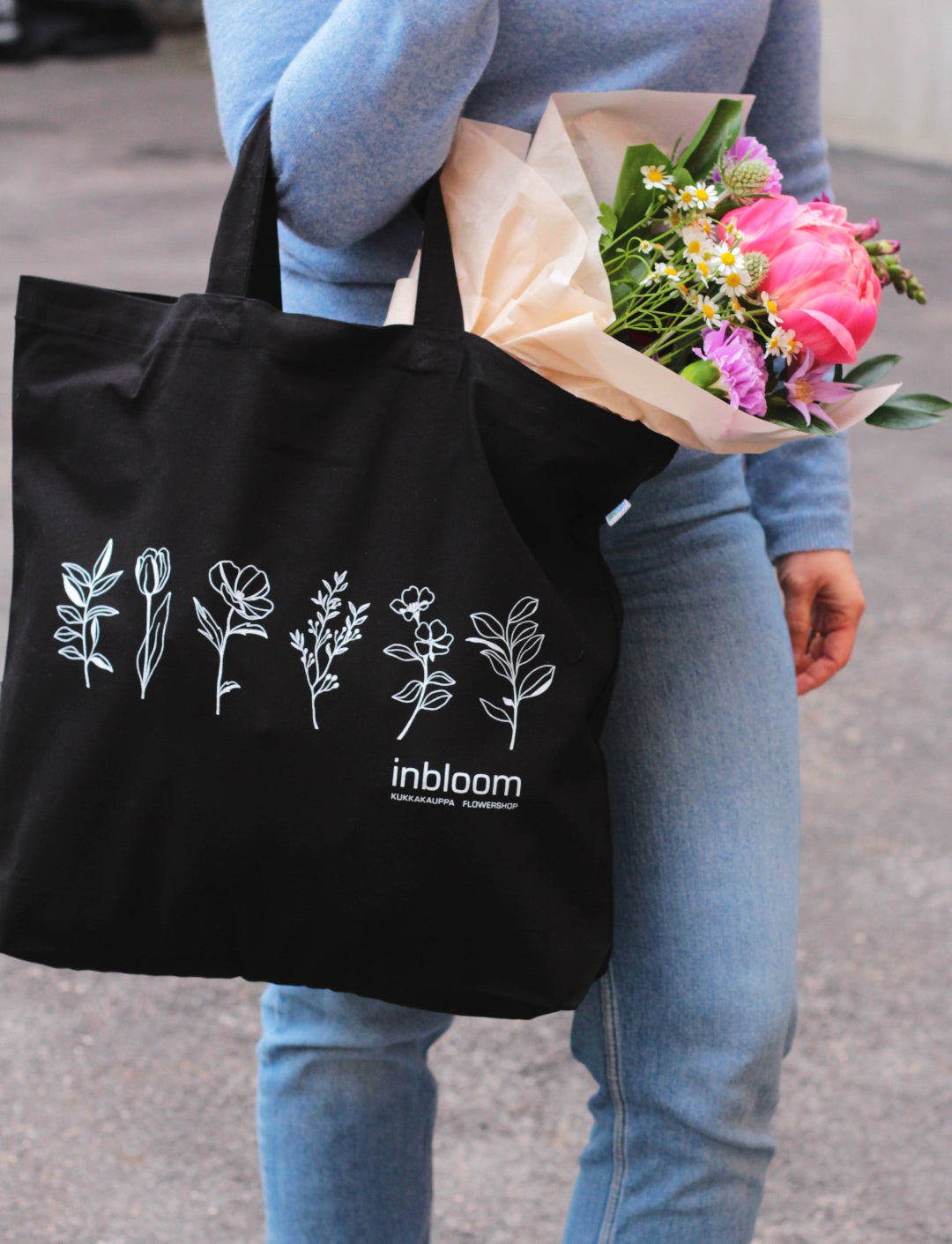 black cotton bag holding bouquet