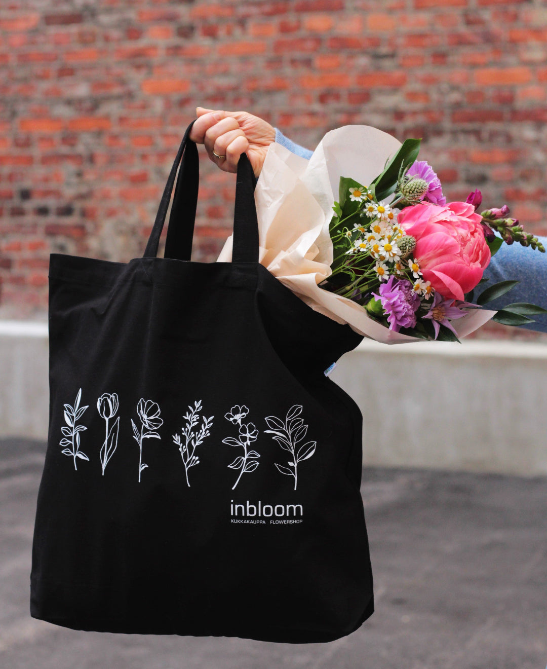 black cotton bag holding bouquet