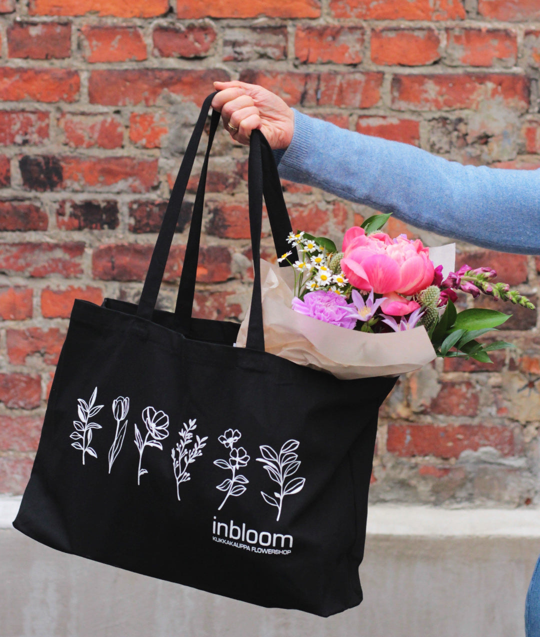 black cotton bag holding bouquet
