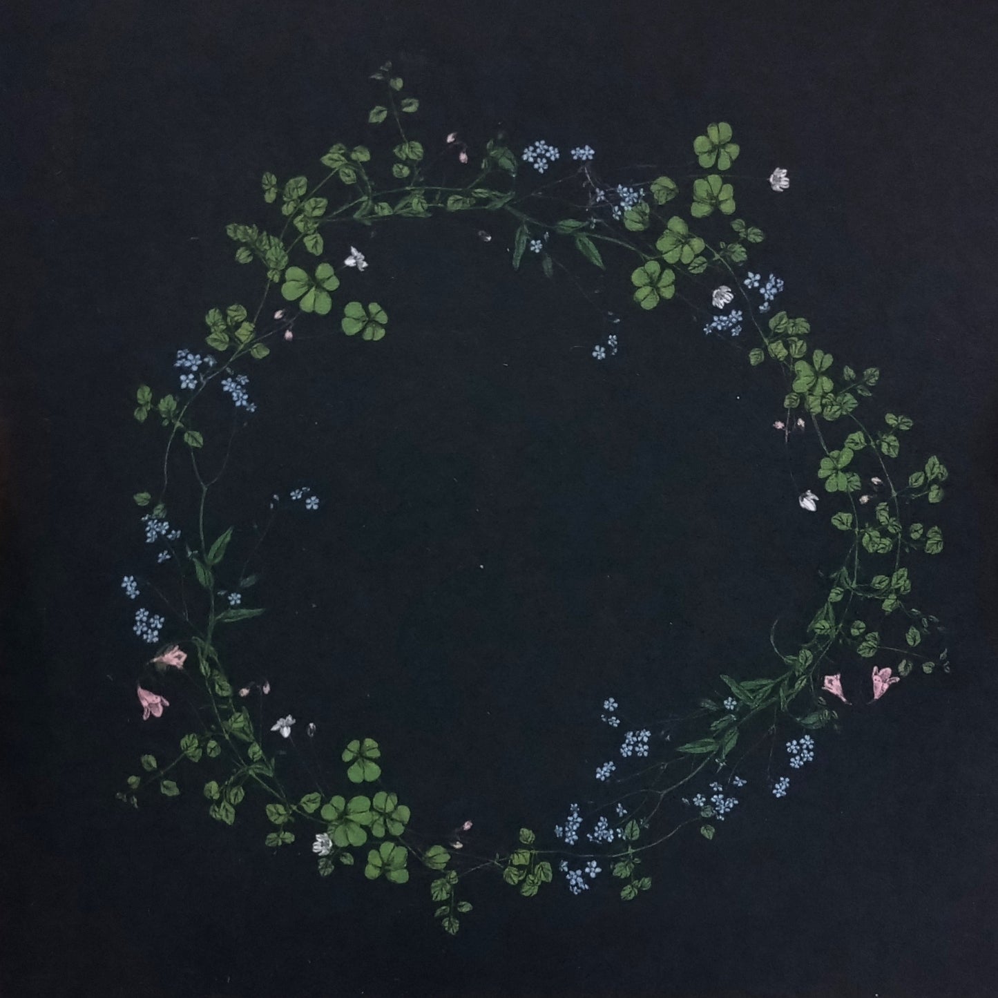 Card - wreath of shamrocks and small flowers on black background